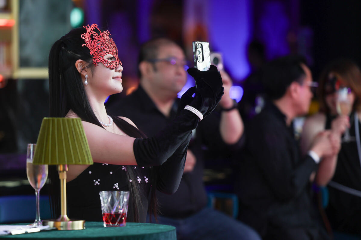 Guest in a masquerade mask photographing the room at an evening event in Singapore