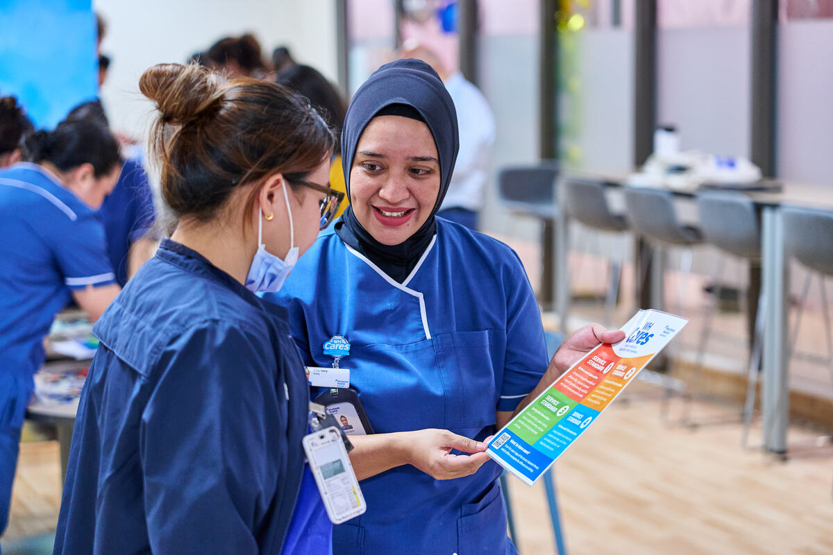Staff reading branded campaign collateral at a Singapore workplace roadshow