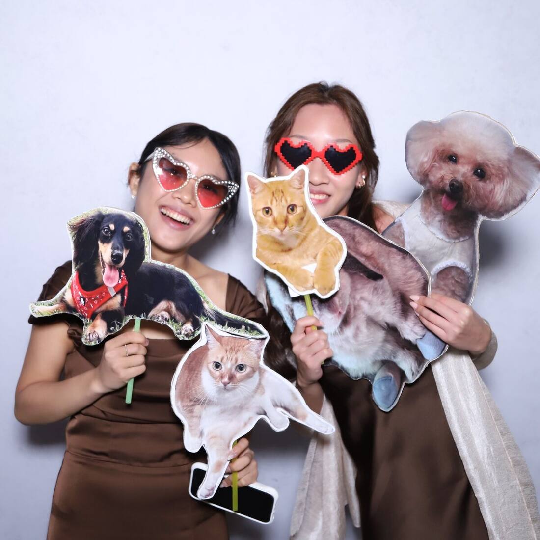 Guests in heart-shaped glasses with fun props at a celebration photobooth